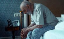 genitore anziano seduto sul letto, triste